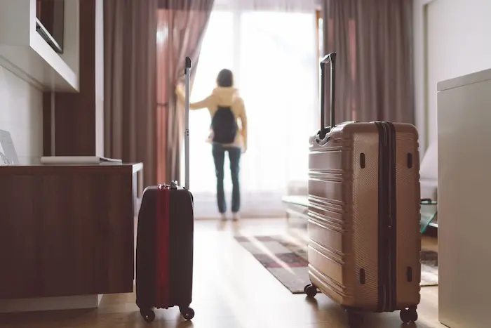 Voyageur devant une grande fenêtre avec bagages, scène qui illustre l’intérêt d’un investissement dans une résidence de tourisme moderne et rentable
