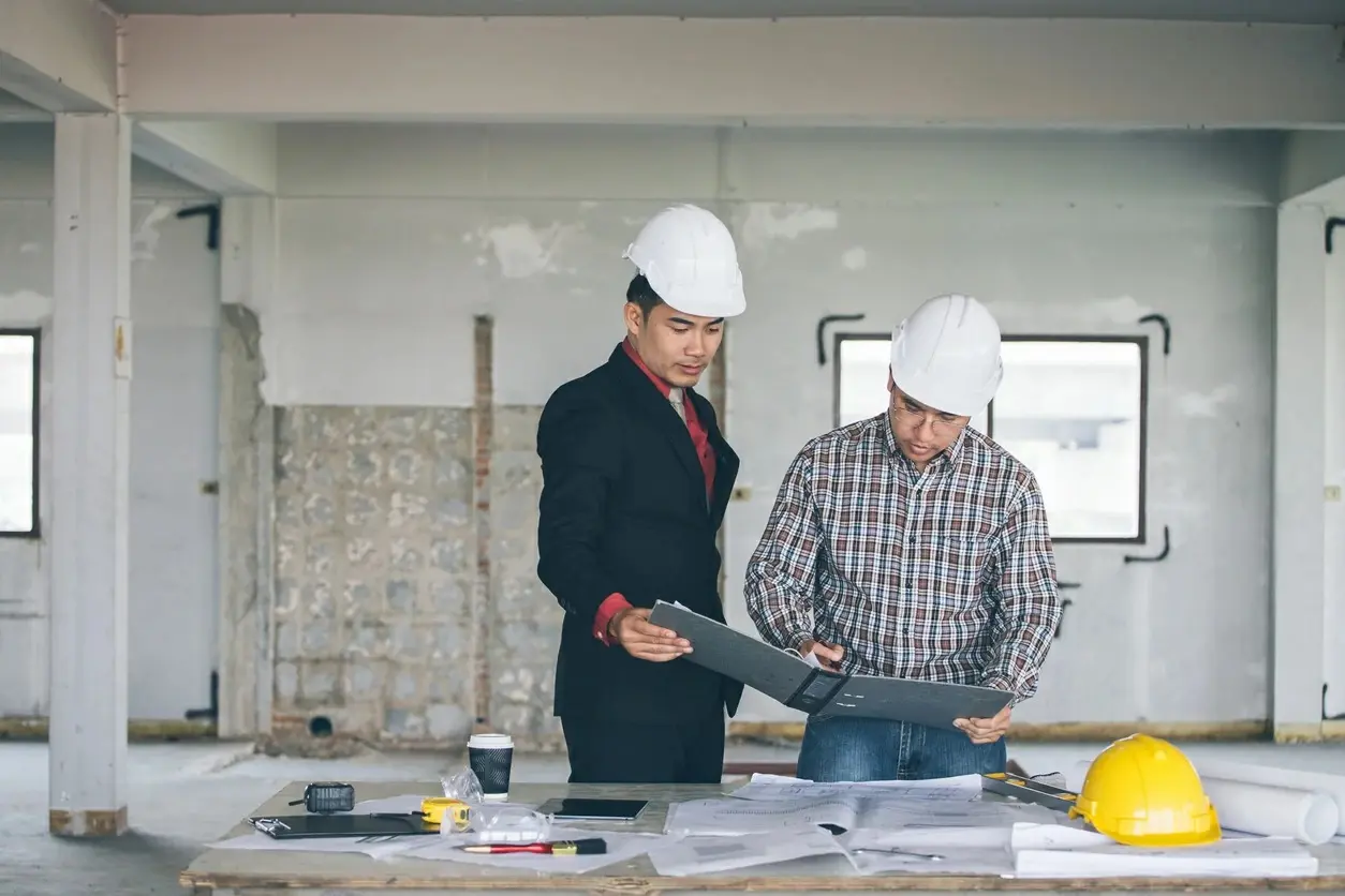 Professionnels du bâtiment vérifiant les plans d’un programme neuf couvert par la garantie décennale sur un chantier VEFA.