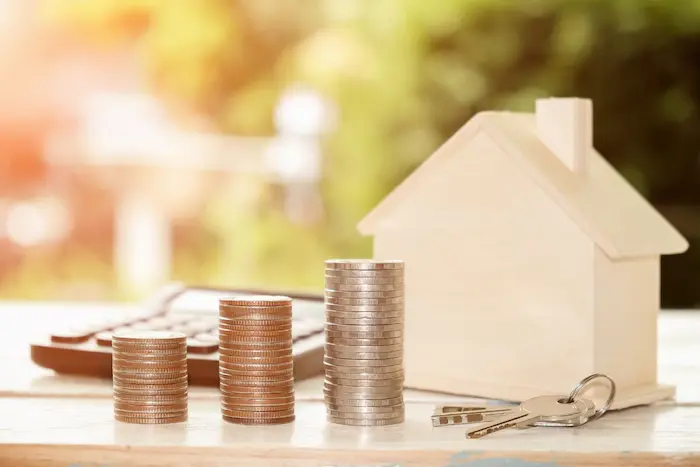 Trois piles de pièces croissantes devant calculatrice, image illustrant le TAEG actuel comme indicateur du coût global d’un crédit immobilier.