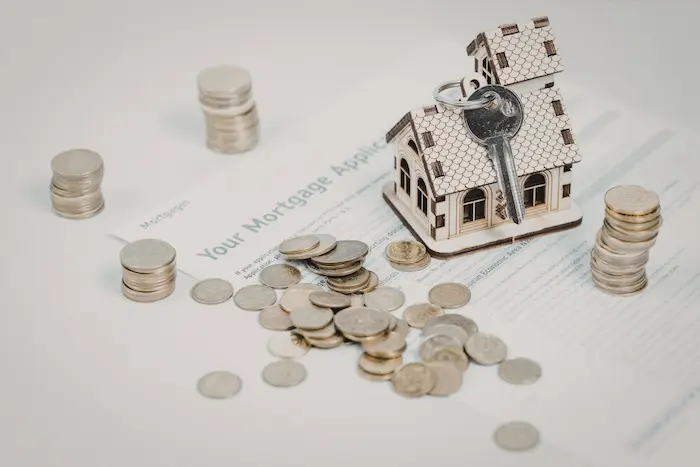 Maquette de maison posée sur un dossier de prêt, pièces et clé illustrant le calcul du taux d’intérêt pour un prêt immobilier.