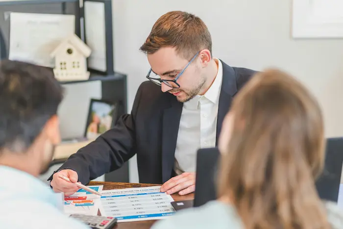 Conseiller en costume montrant un tableau de taux immobiliers, image illustrant le calcul d’un prêt immobilier avec PTZ.